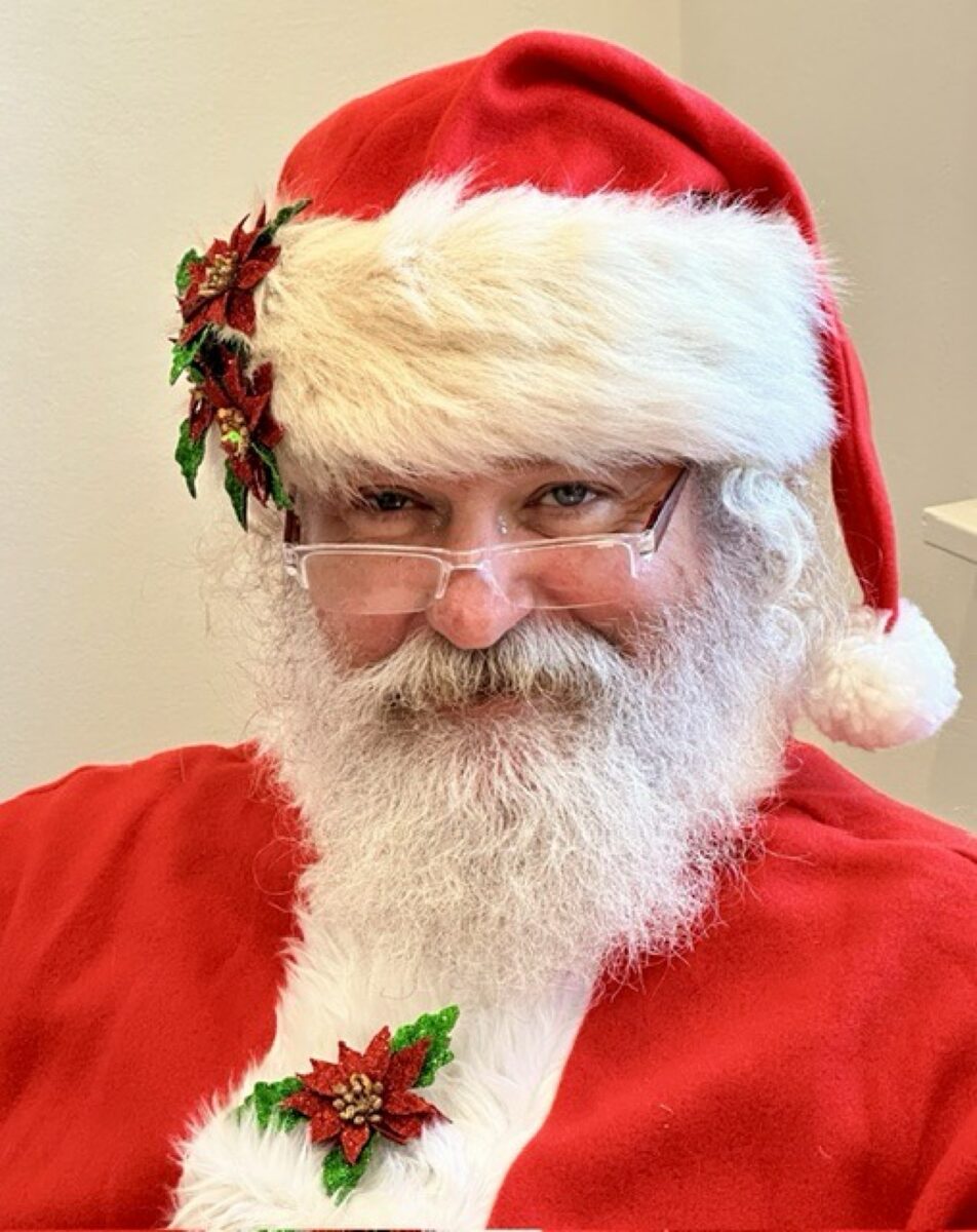 Close-up of Santa smiling with glasses and poinsettia